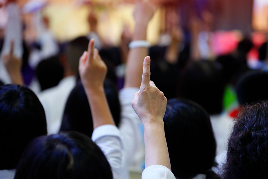 people raising their hands to bid at a property auction
