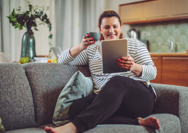 Blonde white woman in stripy jumper looking at Bond Wolfe Auction website on her tablet at home
