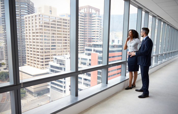 A man and a woman staring out of a window at commercial property