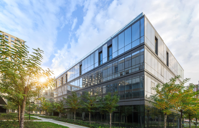 A building of commercial property with reflective windows surrounded by trees